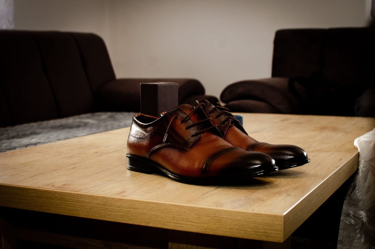 Pair of brown leather oxford shoes on a wooden coffee table in a living room
