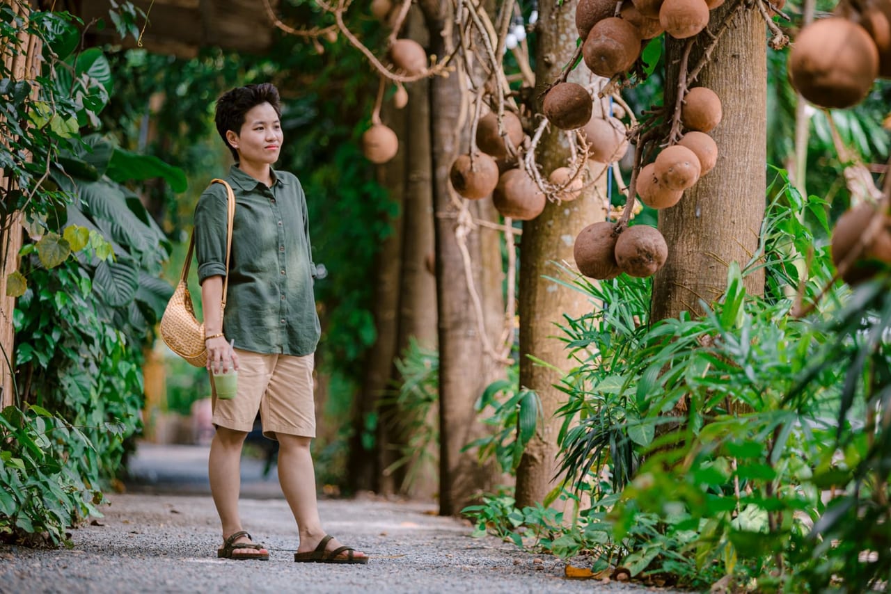 Person in brown sandals and a green shirt standing on a gravel garden path