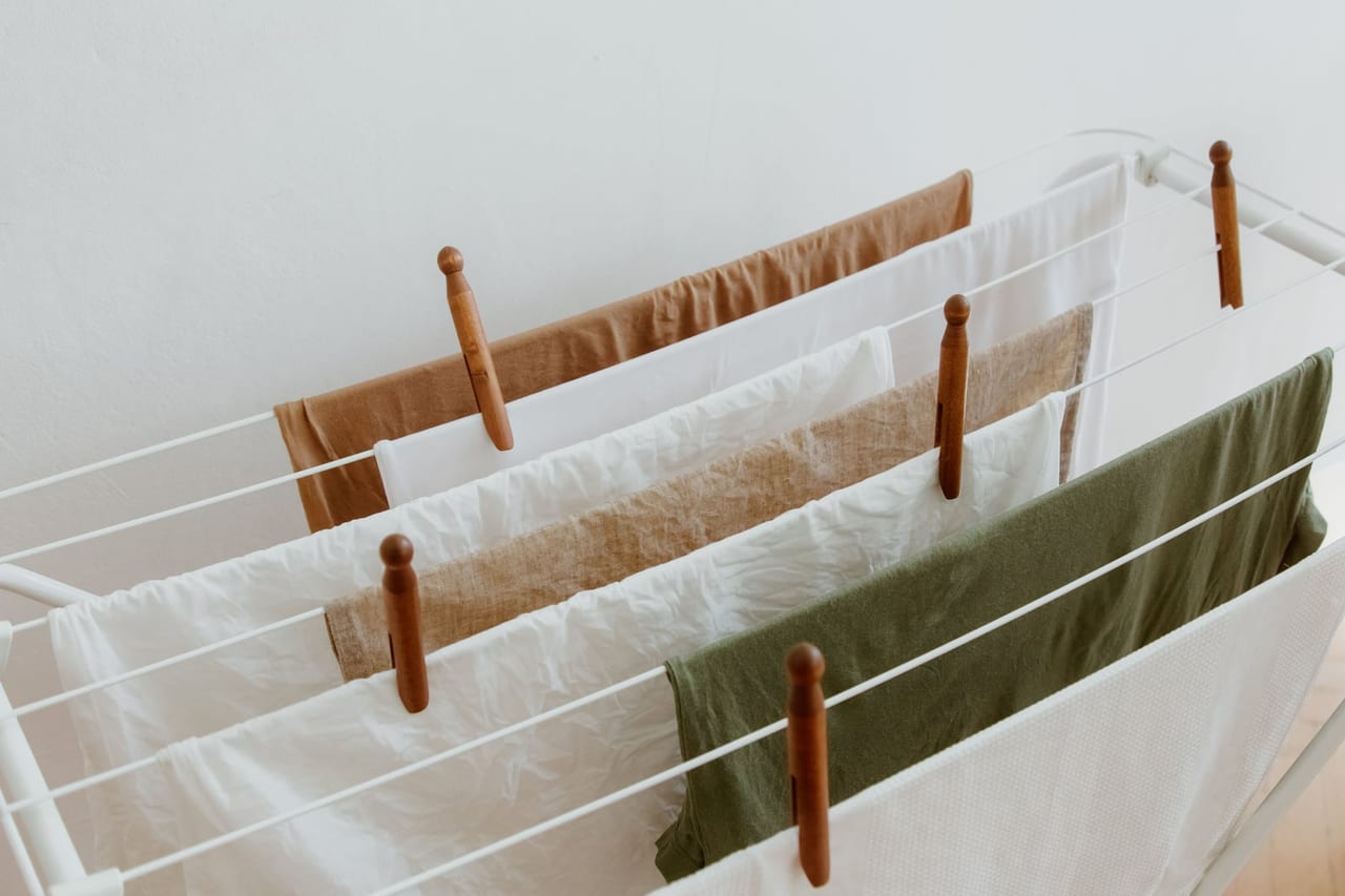 Laundry hung to air-dry on a white indoor rack, held with wooden clothespins