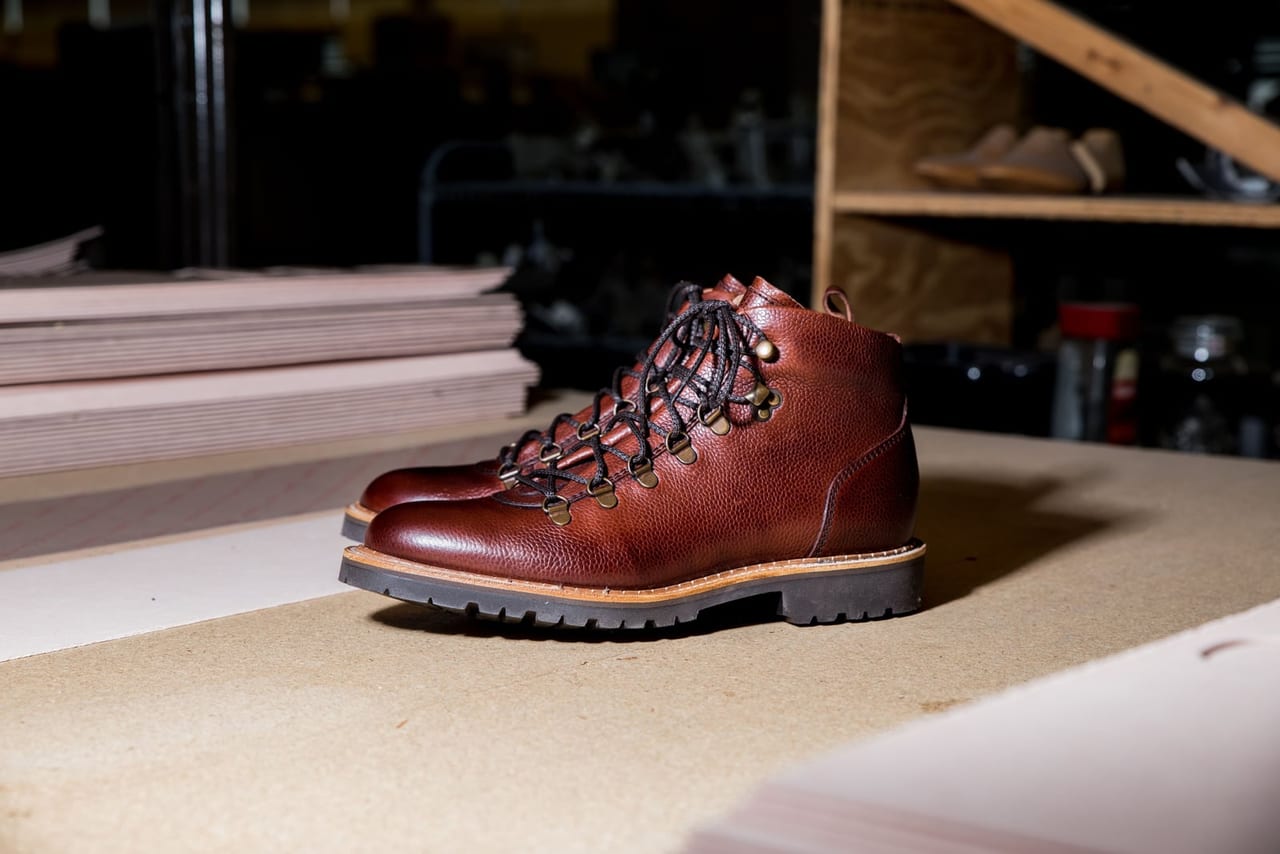 Brown leather lace-up boots with a deep, lugged rubber sole on a workshop table