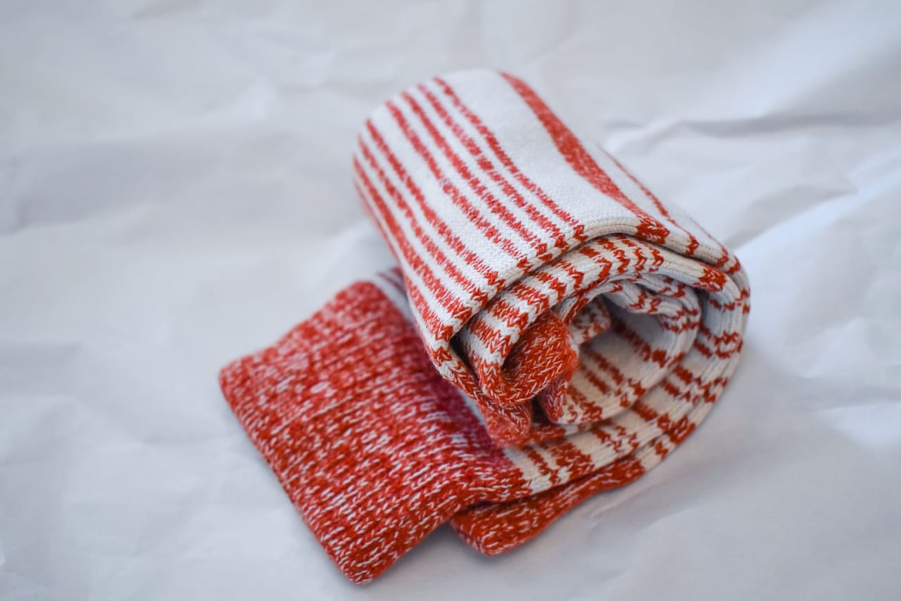 A pair of striped red and white socks rolled together on crumpled white paper