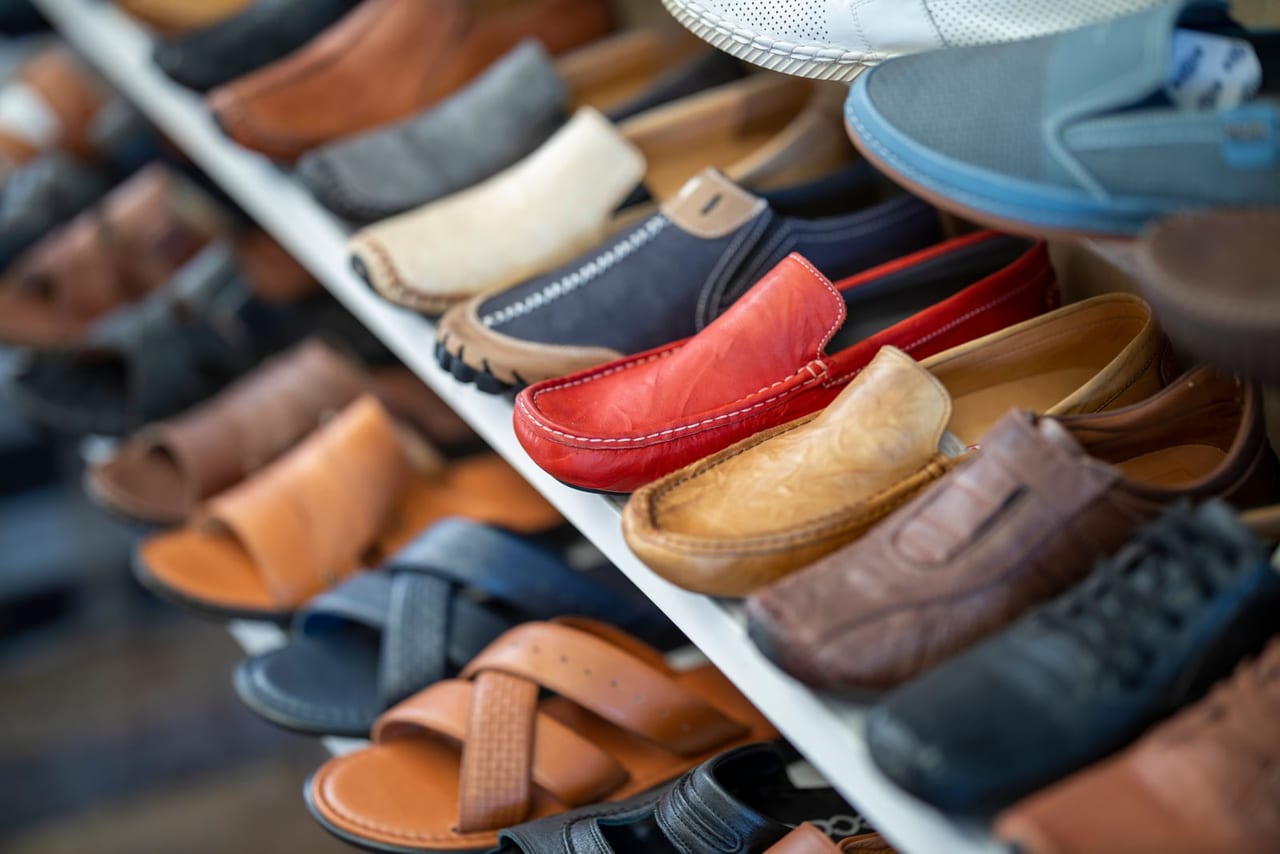 Rows of leather loafers, sandals and sneakers in many colors on a store shelf