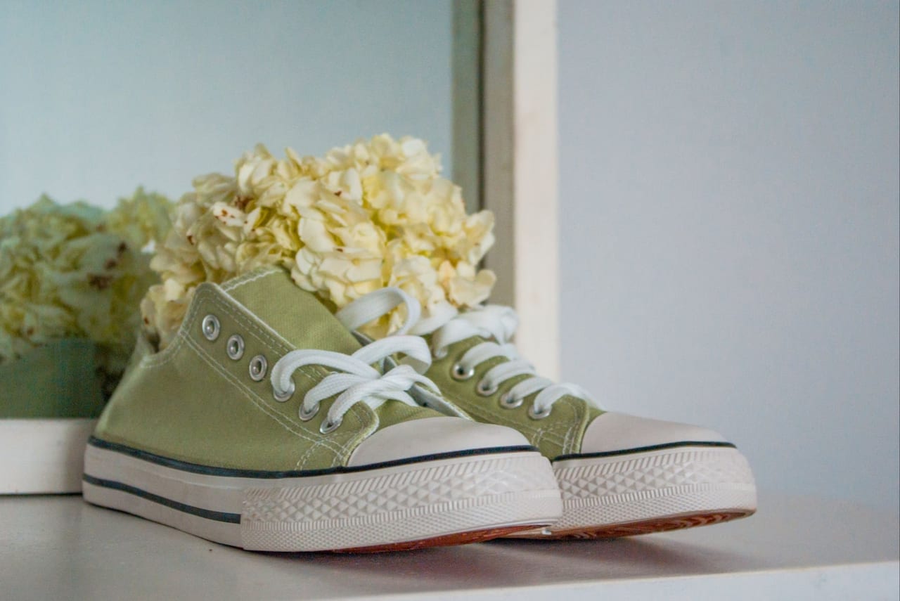 A pair of green canvas sneakers with white hydrangeas tucked inside