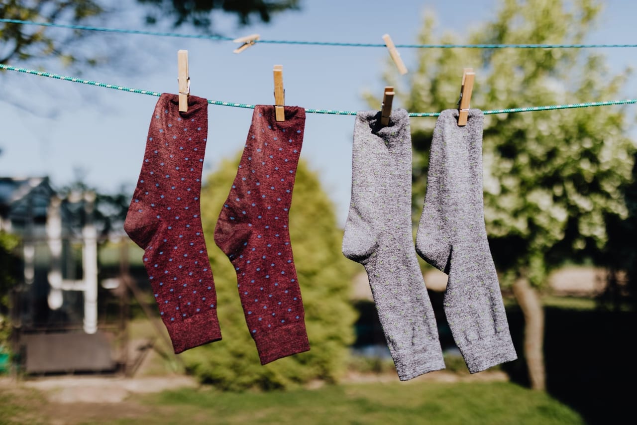 Two pairs of socks pinned to a clothesline with wooden clothespins on a sunny day