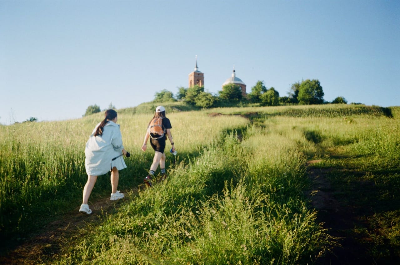 Two women seen from behind walking up a grassy hillside path in sneakers